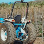 Trator azul parado em um campo agrícola durante o dia.