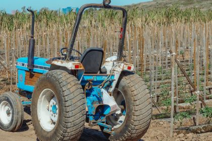 Trator azul parado em um campo agrícola durante o dia.