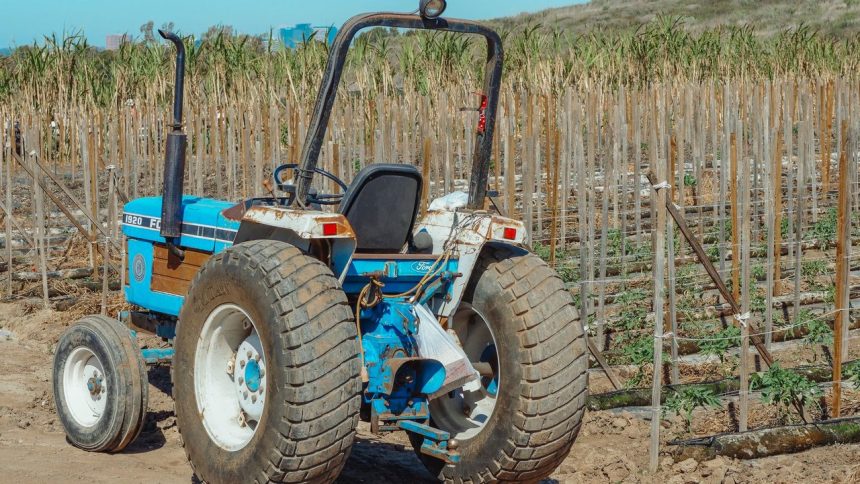 Trator azul parado em um campo agrícola durante o dia.