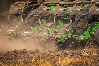 Máquina agrícola semeia um campo de solo seco durante o plantio.